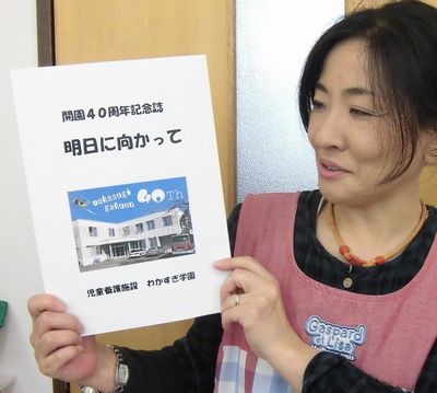 開園４０周年記念誌「明日に向かって」を手にする神裕子支援課長